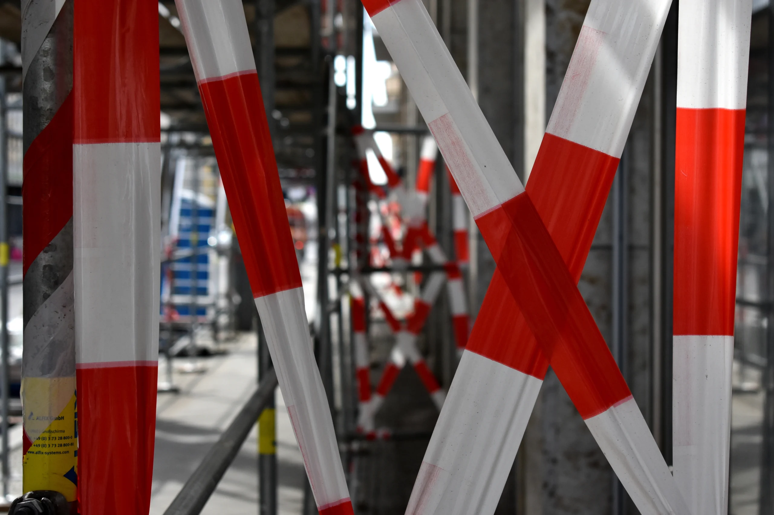 Cintas de precaución en blanco y rojo decoran un andamio.